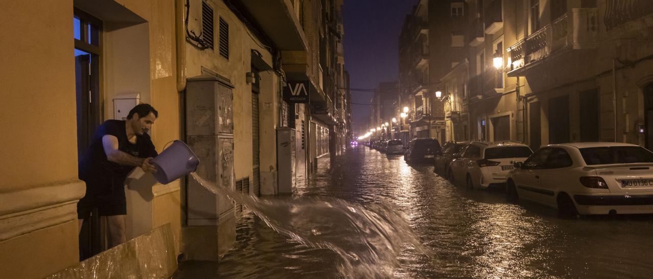 Un vecino saca agua de su casa para tratar de parar la inundación en el Cabanyal Canyamelar durante las lluvias torrenciales del pasado martes.