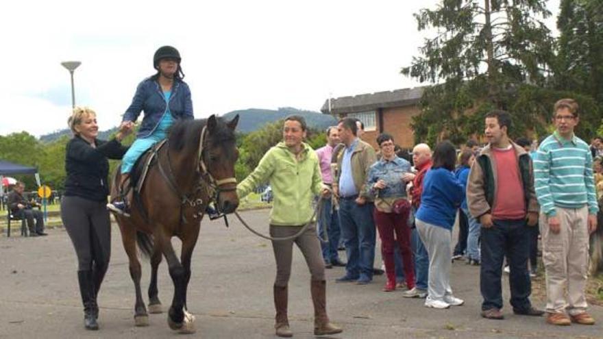 A la izquierda, una usuaria de Fasad, montando a caballo, ayer, en Meres. A la derecha, Marina López acaricia a uno de los perros de terapia. | franco torre
