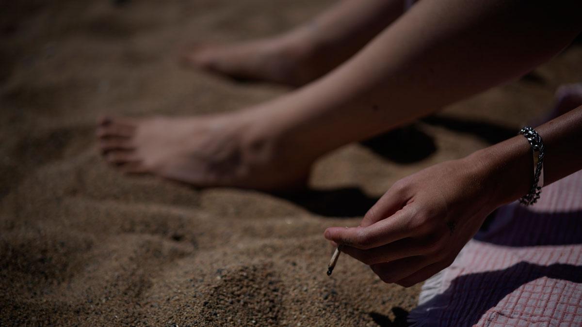 Una persona fumando en la playa de Barcelona.