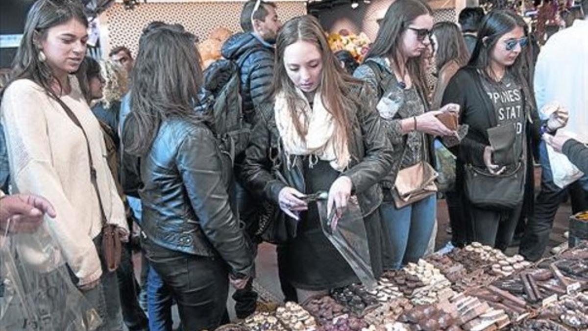 En la Boqueria 8Unas jóvenes estadounidenses compran chocolate en un puesto del mercado, ayer.