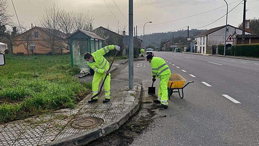 Dos operarios limpian aceras en Lamela.