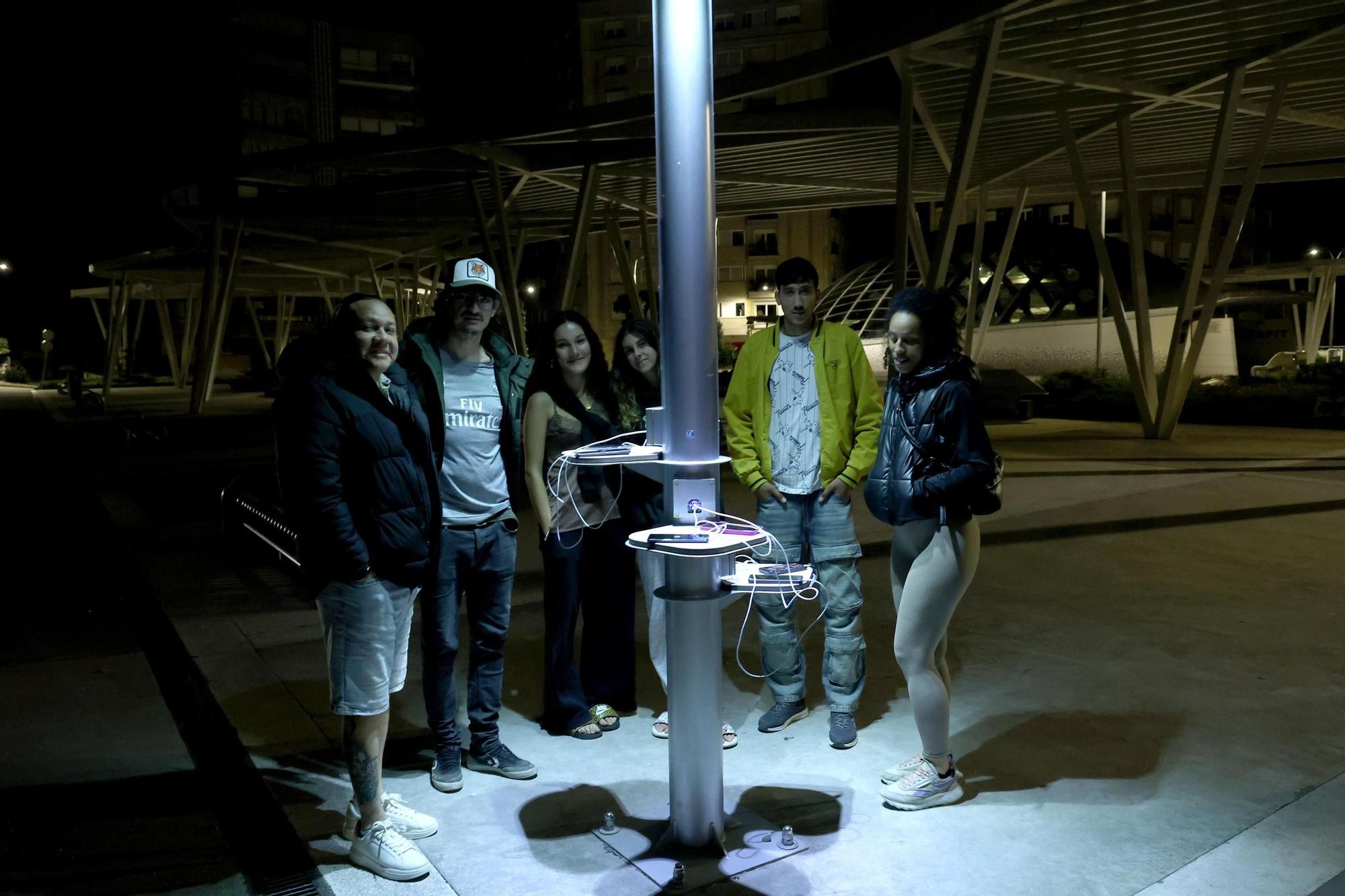 Jóvenes cargan sus móviles en una farola de Vigo