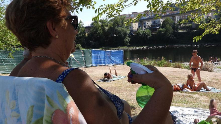 Una mujer se refresca, en la playa de Oira, en el Río Miño (Ourense). | // FERNANDO CASANOVA
