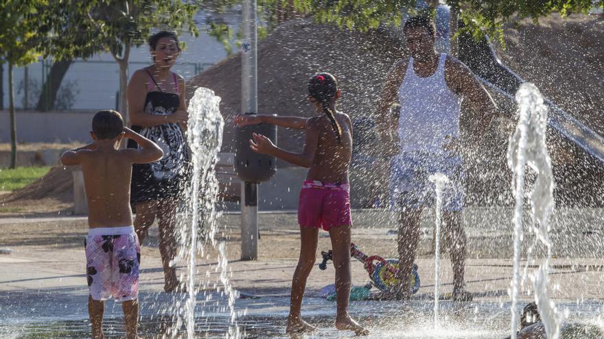 Unos niños se refrescan en una fuente.