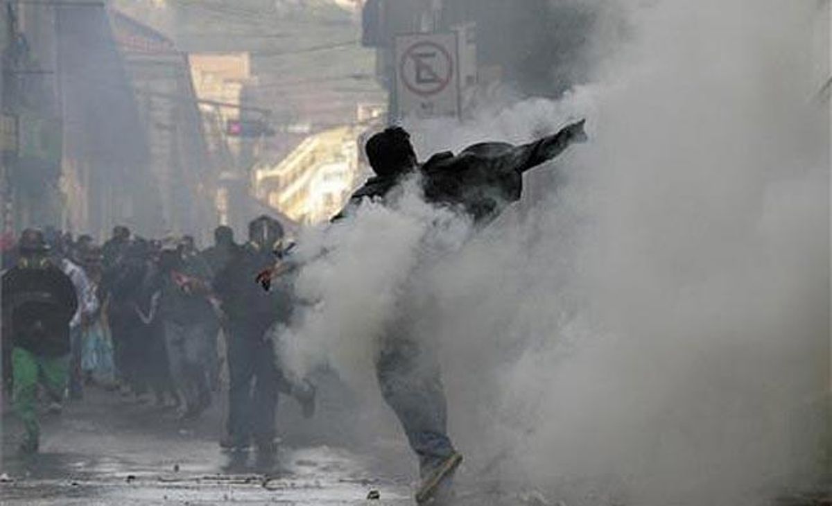 Un manifestant llança un pot de gas lacrimogen de tornada als policies antiavalots durant una protesta a La Paz (Bolívia), el segon dia de vaga per demandar un augment de salari més elevat que el 10% ofert pel Govern.