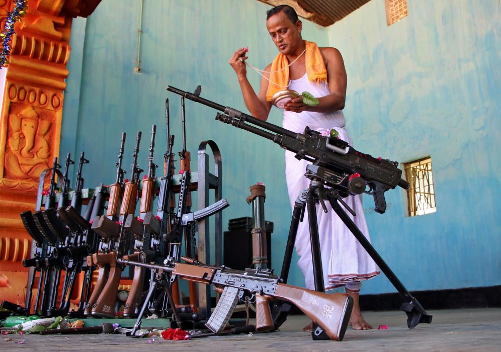 Un sacerdote hindú rinde culto junto a las armas pertenecientes a los rifles estatales de Tripura durante el Vishwakarma Puja, en India.