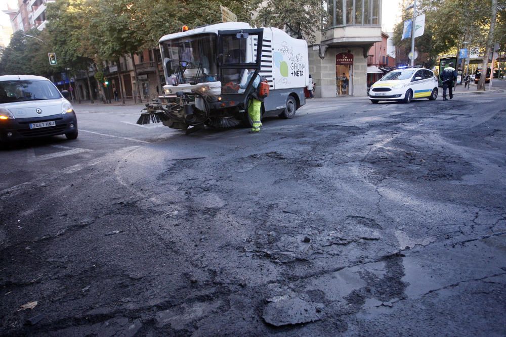 Carrers amb restes de mobiliari urbà cremat, contenidors per terra i treballadors de la brigada treballant