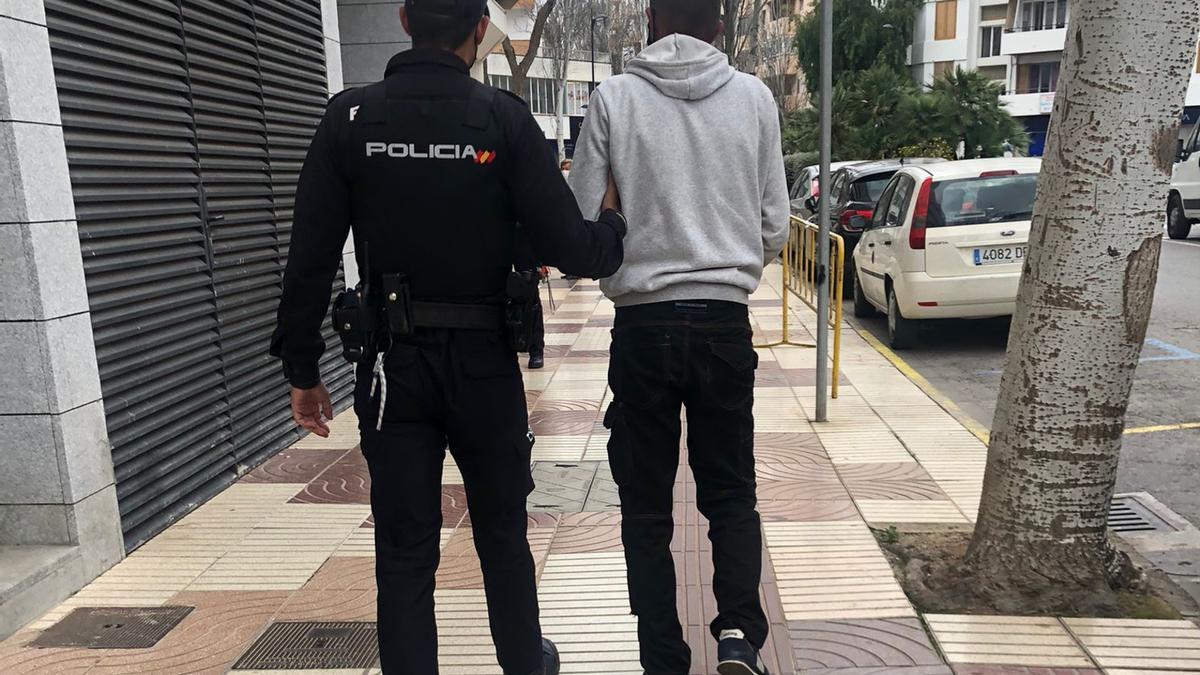 Un policía lleva detenido al presunto autor de las amenazas con la motosierra.