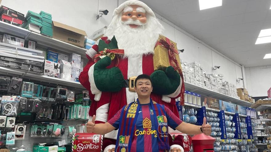 Jony posa en su tienda bajo un Papá Noel gigante, mientras porta la camiseta del Poblense, de la que él es sponsor en categorías inferiores.