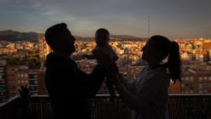 Rubén y su mujer en el balcón de su casa con su hija en brazos.