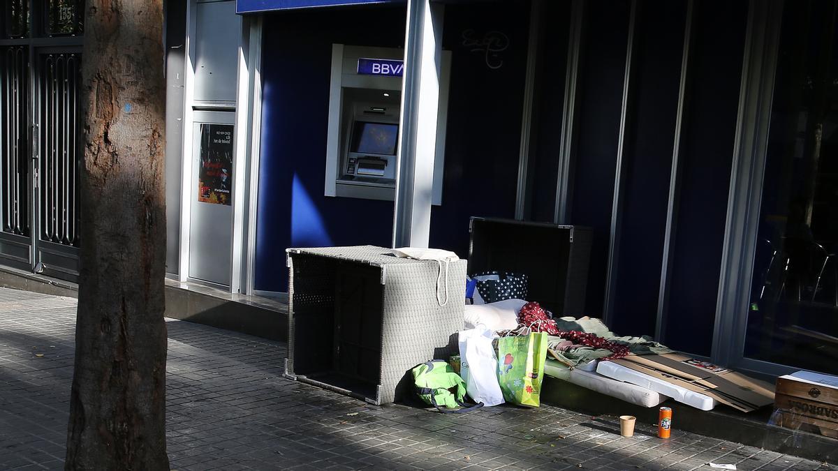 Un hombre duerme en el acceso a una entidad bancaria de la calle Llobregós