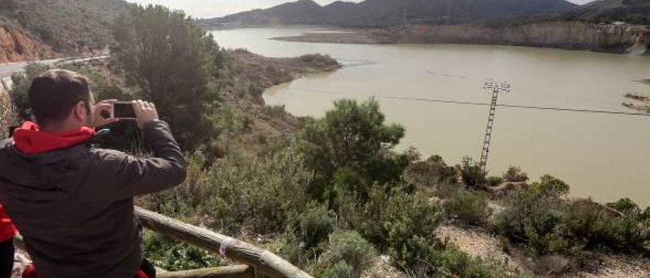 Un hombre fotografía el pantano del Amadorio tras el temporal de nieve y lluvia del pasado mes de enero.