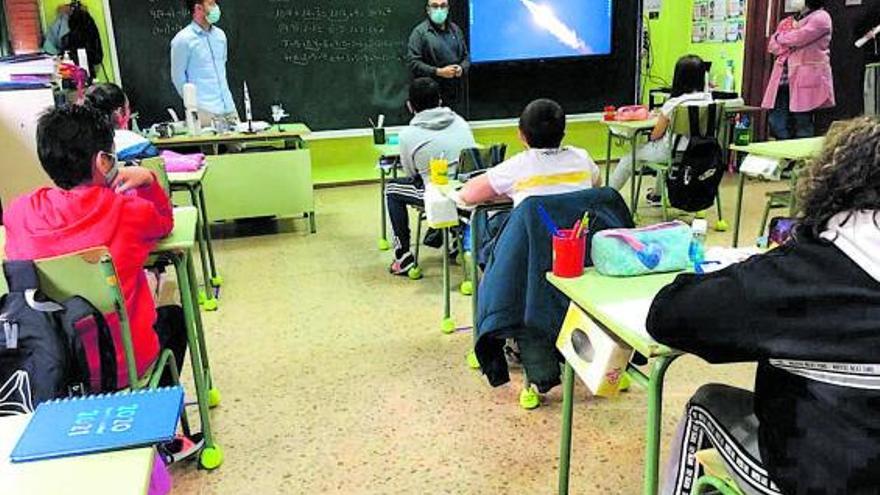Los niños atienden en una clase las explicaciones de un profesor, junto a otros dos compañeros.