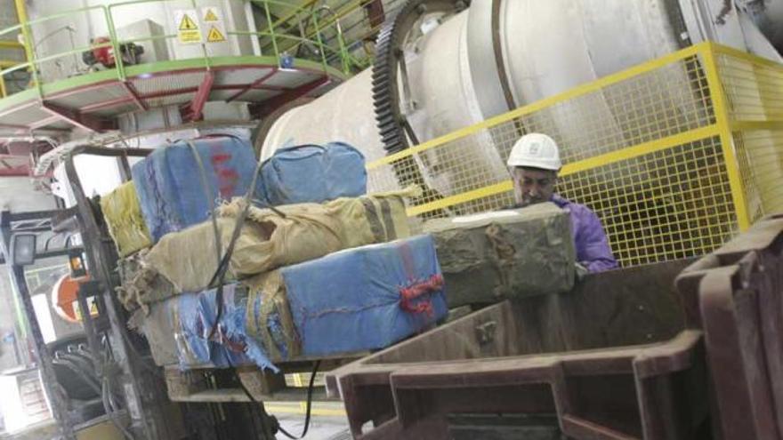 Un operario de Cogersa introduce fardos de hachís en un contenedor antes de destruirlos en el horno.