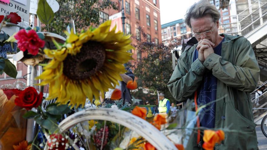 Un hombre reza ante un pequeño memorial a las víctimas.