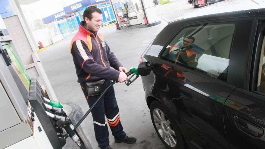 Un trabajador de una gasolinera carga combustible en un vehículo.