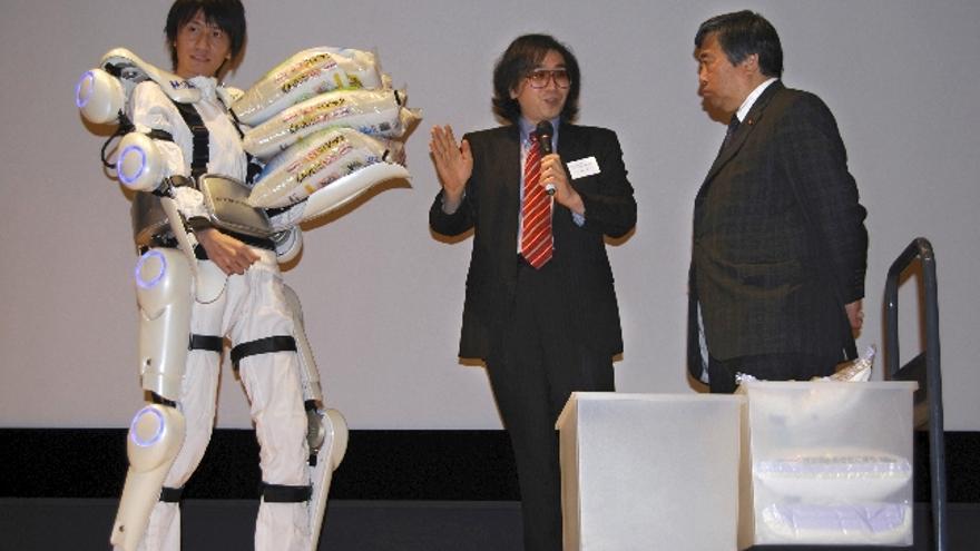 Una empresa japonesa presentó hoy en Tokio un robot-traje, una especie de esqueleto externo cibernético cuyo objetivo es facilitar los movimientos de ancianos y disminuidos físicos. Cuando el usuario se enfunda el invento, bautizado con el nombre de Hal, ve aumentada su fuerza de manera considerable por lo que su creador, Yoshiyuki Sankai (c), cree que tendrá una aplicación comercial en los servicios a la tercera edad. Hal está equipado de varios sensores que intuyen los movimientos del cuerpo, por lo que ayudaría a sus usuarios a ejecutar las acciones que no podrían llevar a cabo por sí solos. En la foto Sanka da explicaciones al secretario general del Ministerio de Educación y Ciencia, Yoshitsugu Harada, mientras se hace una demostración con Hal levantando sacos de arroz.