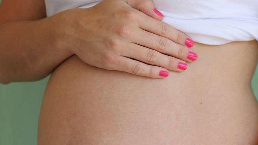 Una mujer embarazada muestra su barriga.