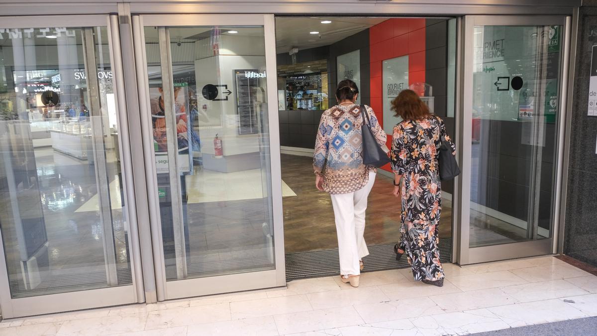 Dos señoras entrando a un gran almacén que tiene puertas automáticas.