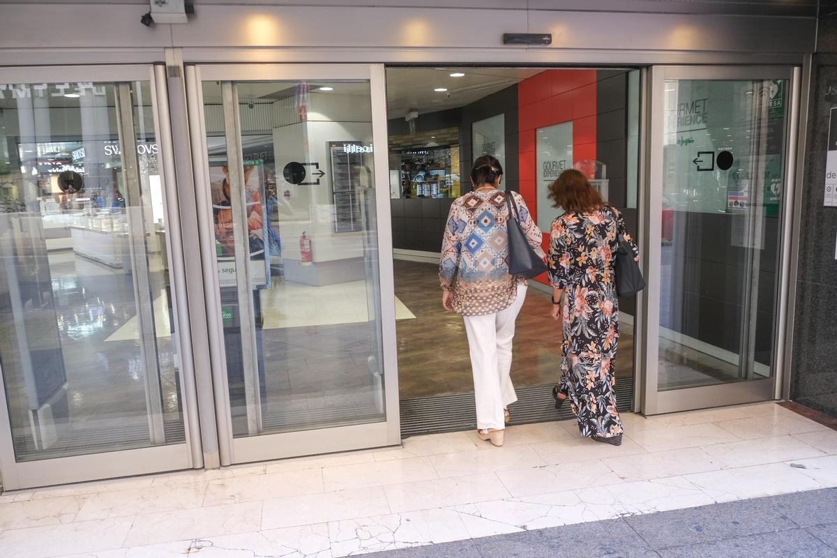 Dos señoras entrando a un gran almacén que tiene puertas automáticas.