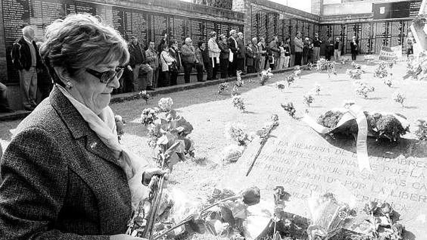 Una mujer, depositando flores, ayer, en la fosa común del cementerio.