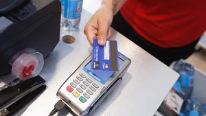 Un usuario paga en el TPV de un comercio con una tarjeta.