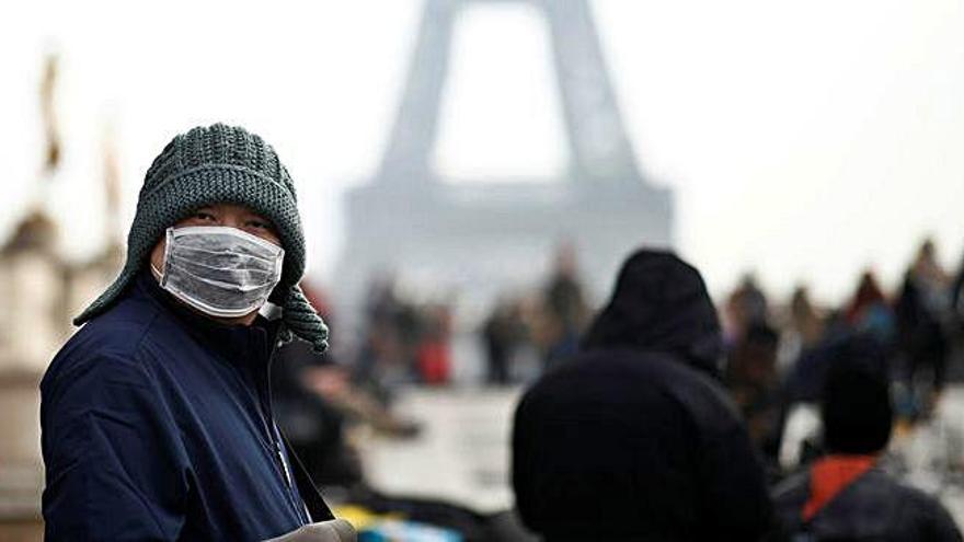 Una dona amb una màscara davant la Torre Eiffel de París després que França confirmés els tres casos de coronavirus.