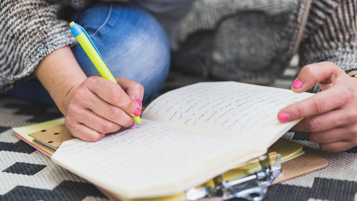 Una joven escribiendo en un cuaderno.
