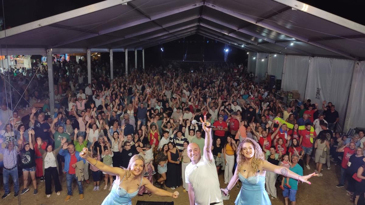 Artistas del Grupo Ideas posan con el campo de la fiesta de Cornellana a rebosar