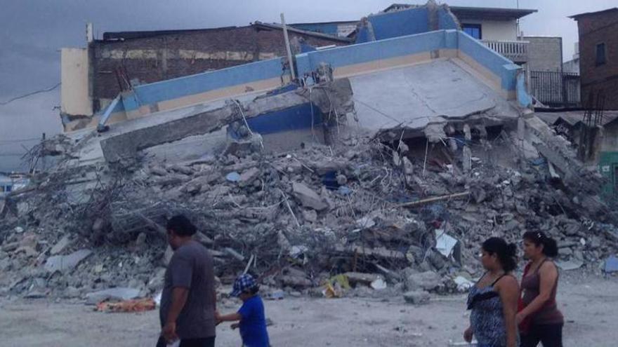 Una familia pasa junto a un edificio derruido en Guayaquil, en una foto tomada por Alejandro Oviedo Alvarado.