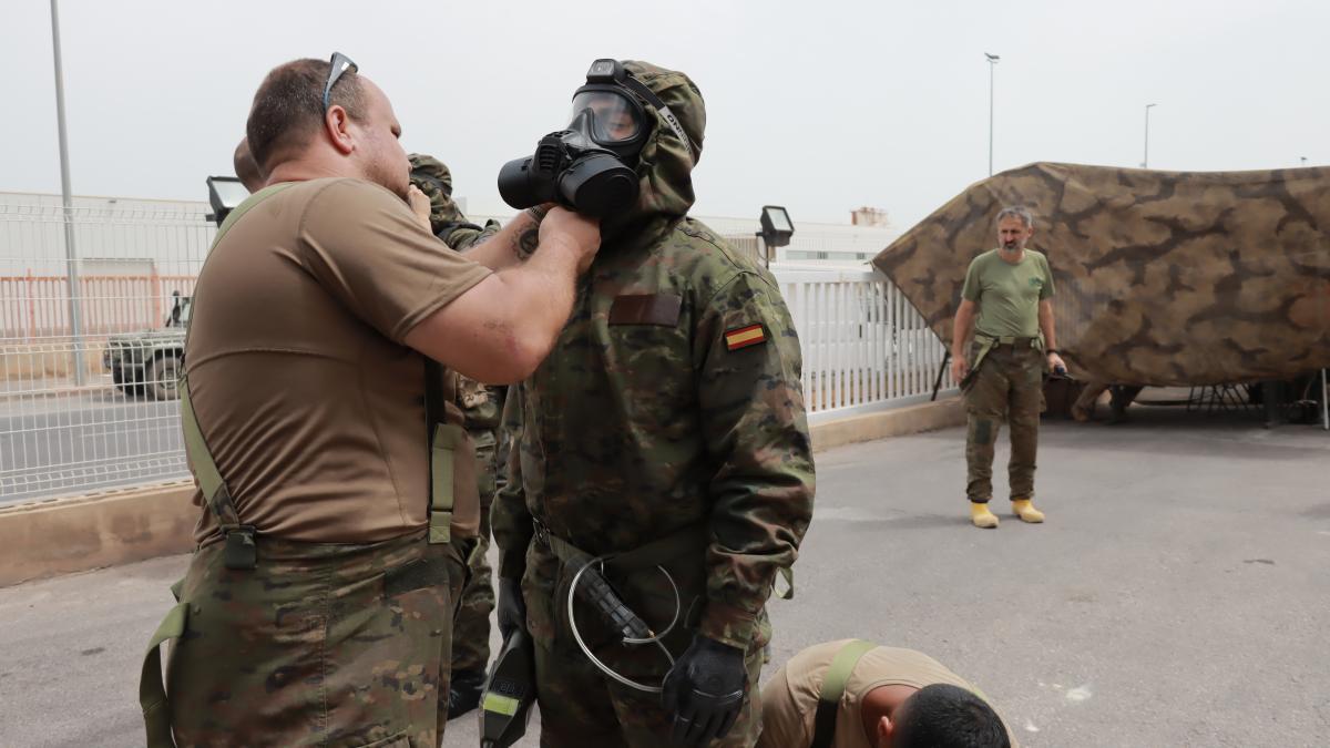 Un militar ayuda a otro a poner su máscara de gas, imprescindible para evitar la inhalación de gases y sustancias tóxicas.