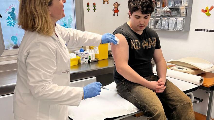Una sanitaria pone una vacuna a un joven.