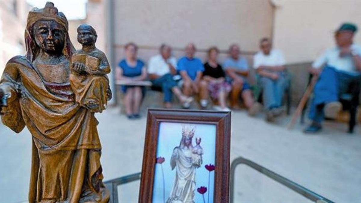 Un símbolo del pueblo 8 Vecinos de Rocallaura sentados en un banco, con una reproducción y una fotografía de la virgen del Tallat delante.