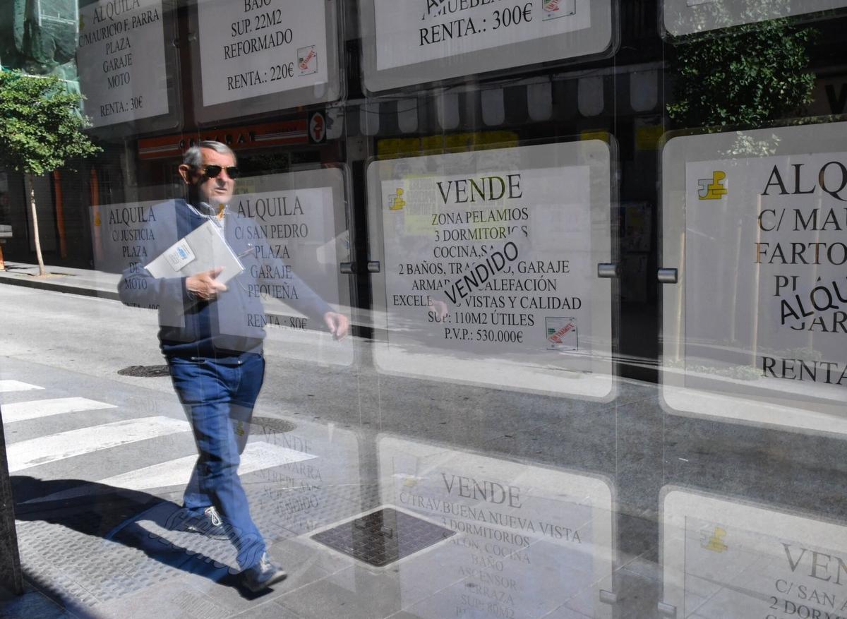 Un hombre pasea ante una inmobiliaria en A Coruña.