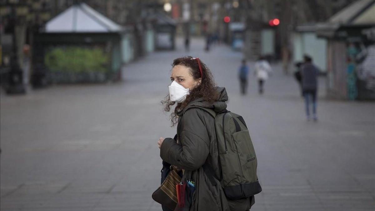 coronavirus Barcelona. Una mujer con mascarilla en la Rambla vacía