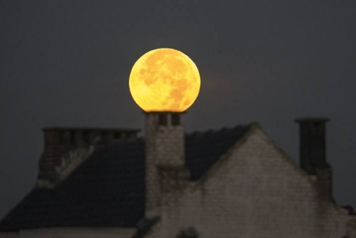 A supermoon appears behind a house after a total "supermoon" lunar eclipse in Brussels