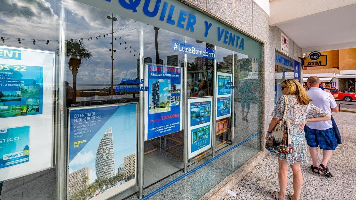 Dos personas mirando las ofertas de una inmobiliaria de Benidorm.