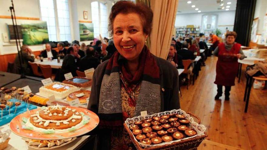 Idita Suárez, que ganó tres premios del concurso de postres, muestra sus recetas. Al fondo, la Casa de Cultura de Bueño durante la corderada.