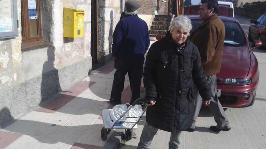 Una vecina carga dos garrafas de agua mineral sobre un improvisado carro de fabricación casera.