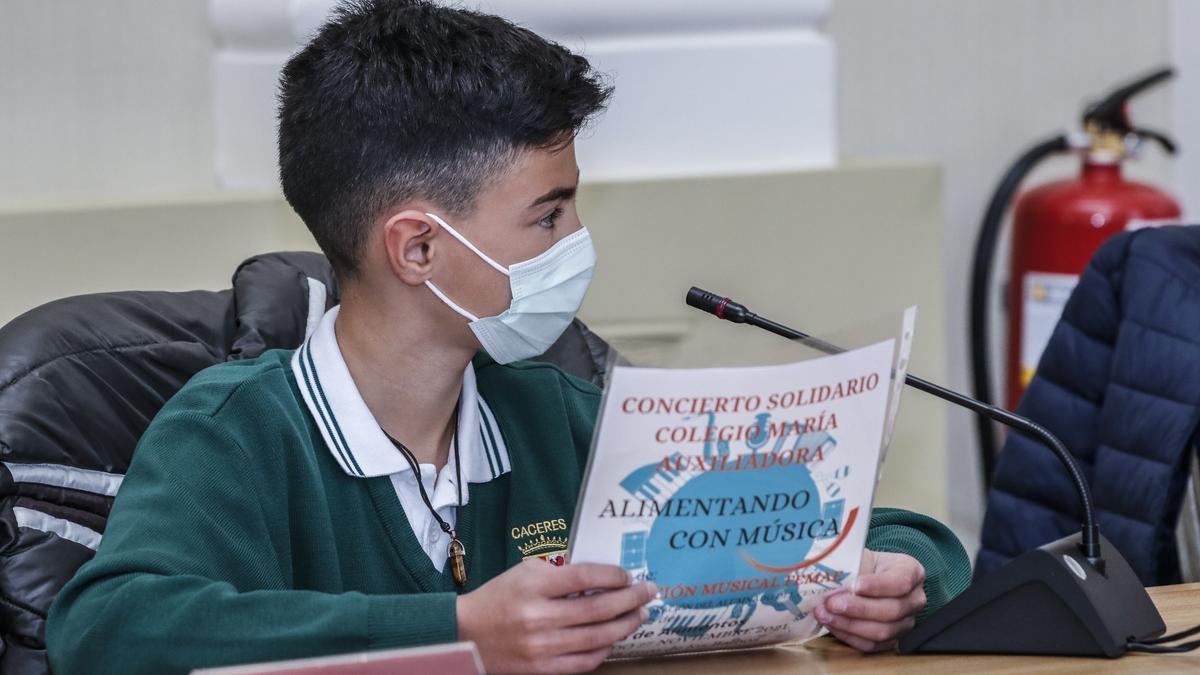 Un alumno del colegio María Auxiliadora durante el pleno de la infancia con el cartel.