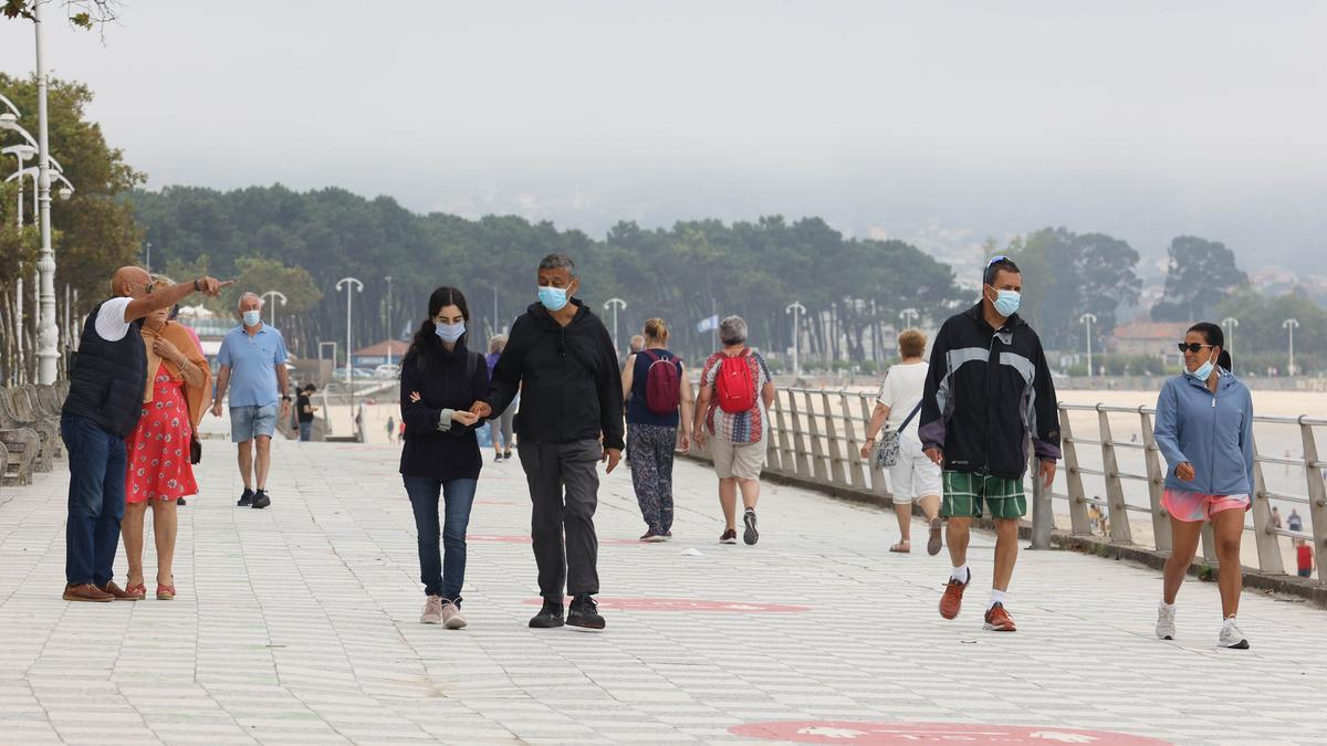 Personas caminando por la playa de Samil.