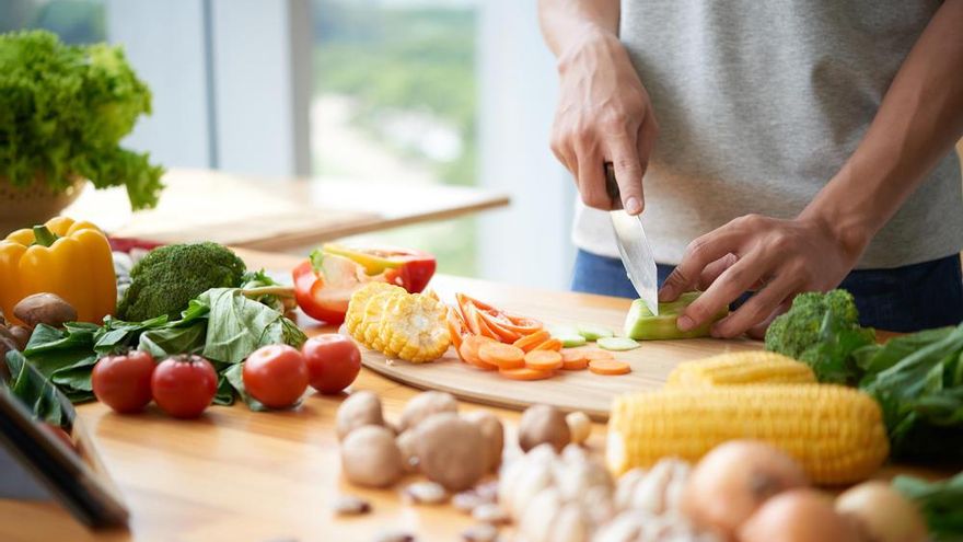 Un hombre cocina con alimentos saludables.