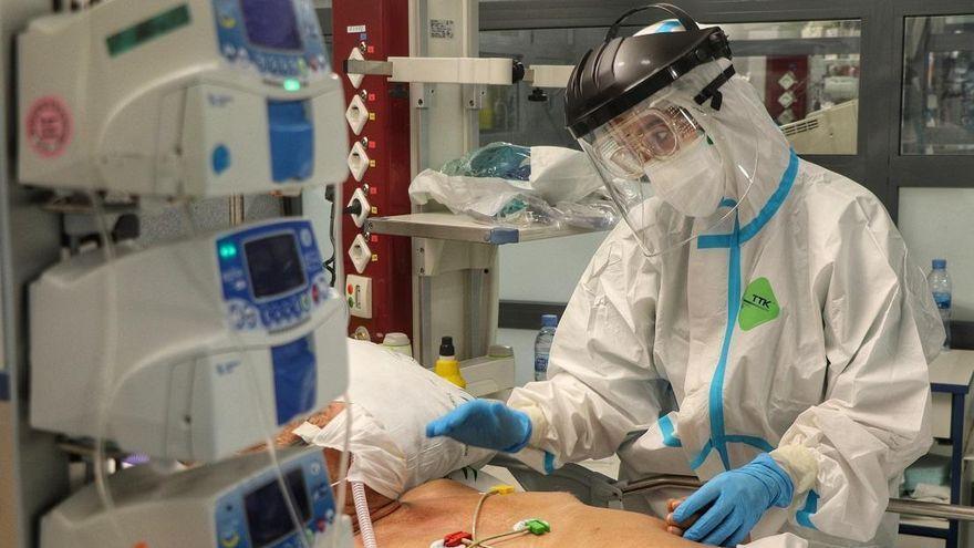 Un profesional sanitario atiende a un paciente en una UCI.