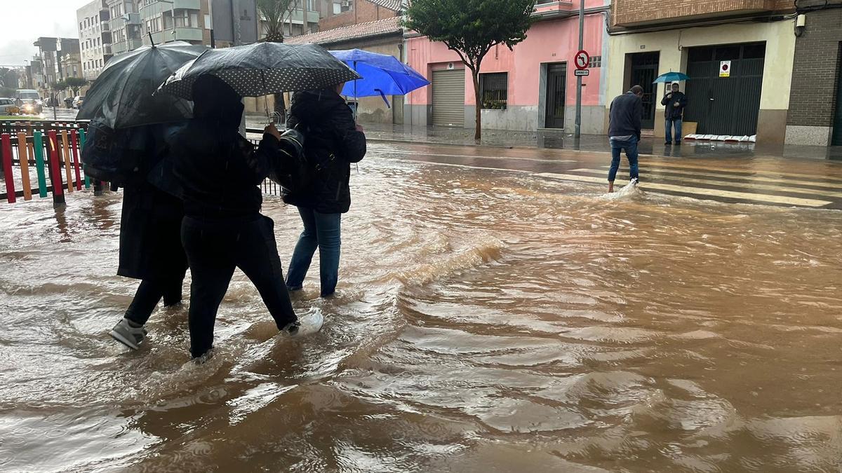 Varias personas cruzan una calle inundada de Nules, con el agua por las espinillas.