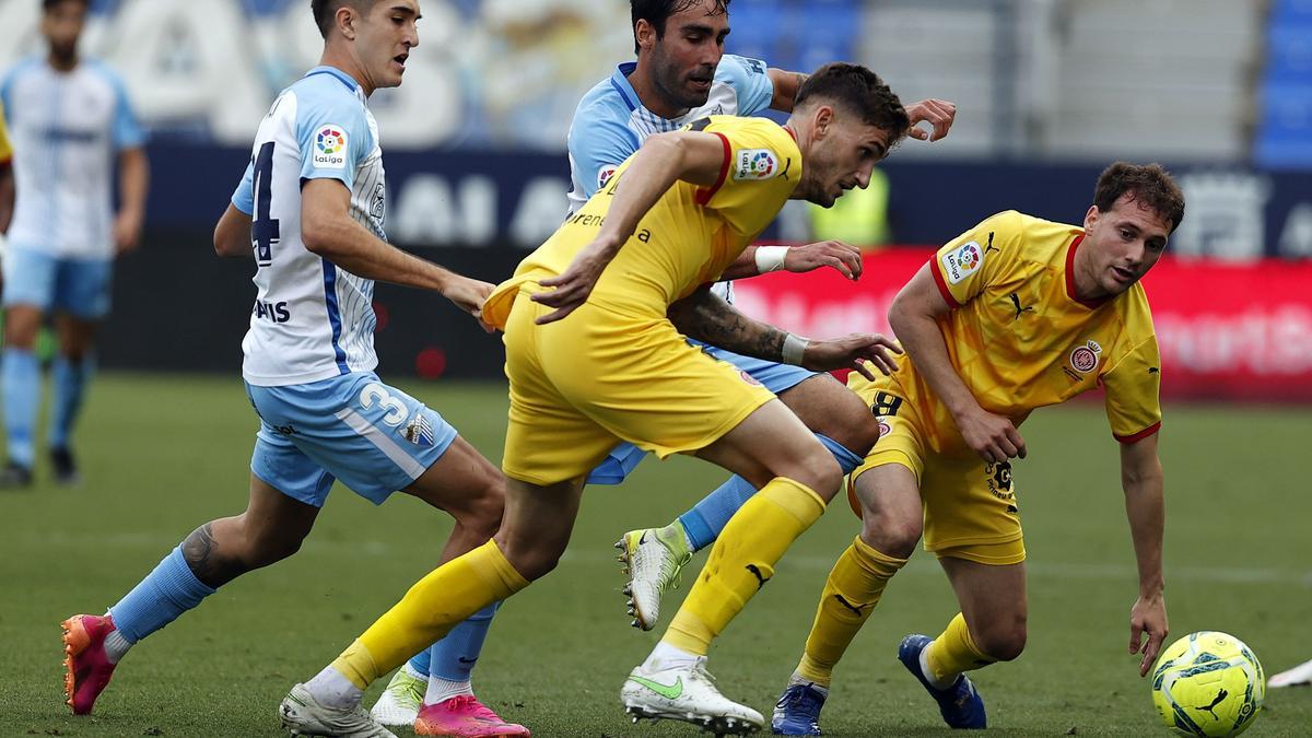 Los jugadores del Girona defendiendo la posesión del balón ante el acoso del Málaga.