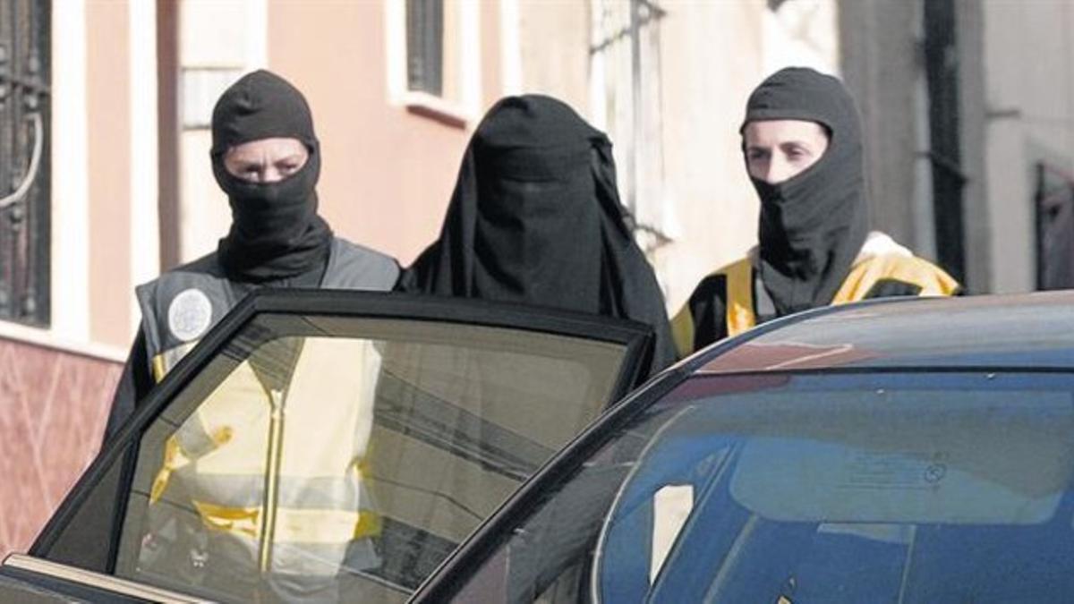 Dos mujeres de la policía trasladan a una de las detenidas en la redada de ayer, en que fue arrestada una joven en Barcelona.