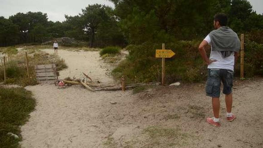Un hombre observa la valla rota y a una persona sobre la duna. // NP