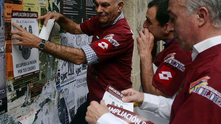 Ricardo Tilve, Ruibal y José Manuel Fernández pegan carteles en una calle de la ciudad. // Rafa Vázquez