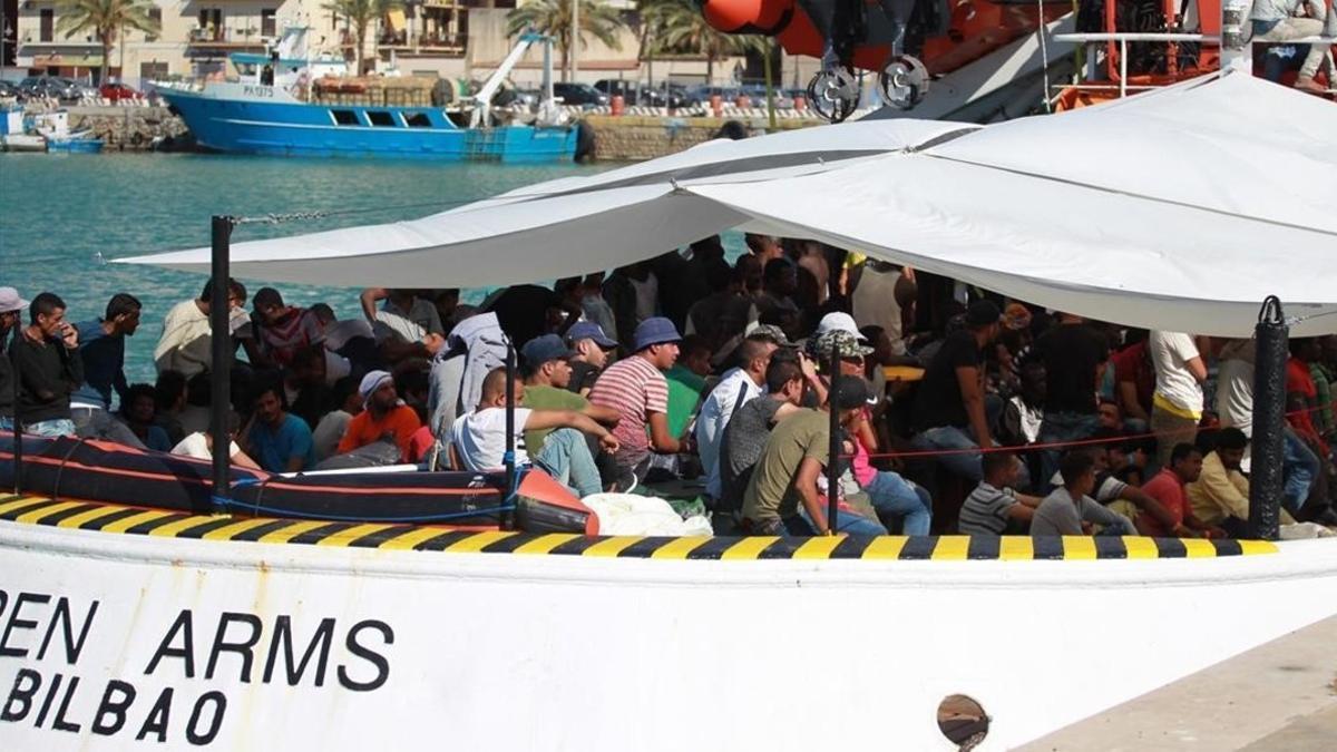 Unos inmigrantes esperan desembarcar de uno de los barcos de Open Arms.