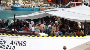 Unos inmigrantes esperan desembarcar de uno de los barcos de Open Arms. 